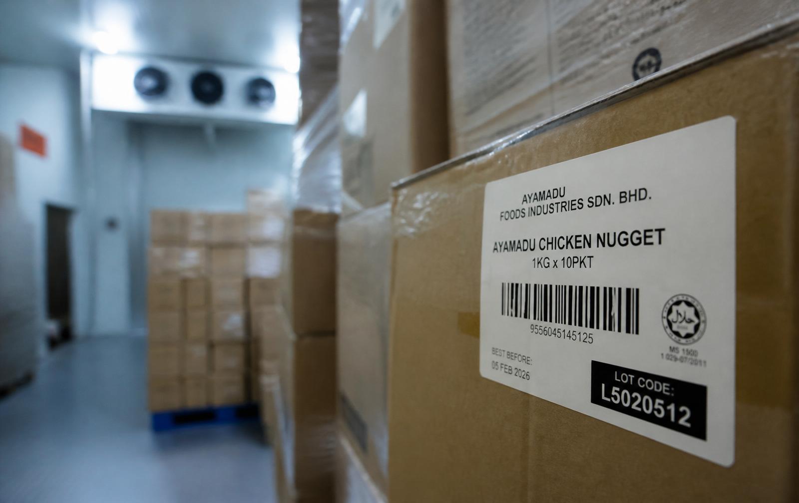 Close-up of a finished-goods carton label with a lot code sticker inside a chilled cold-room, pallets softly blurred behind.